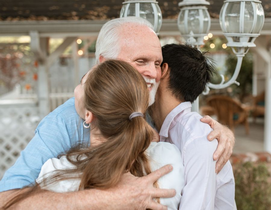An older man embracing his adult children